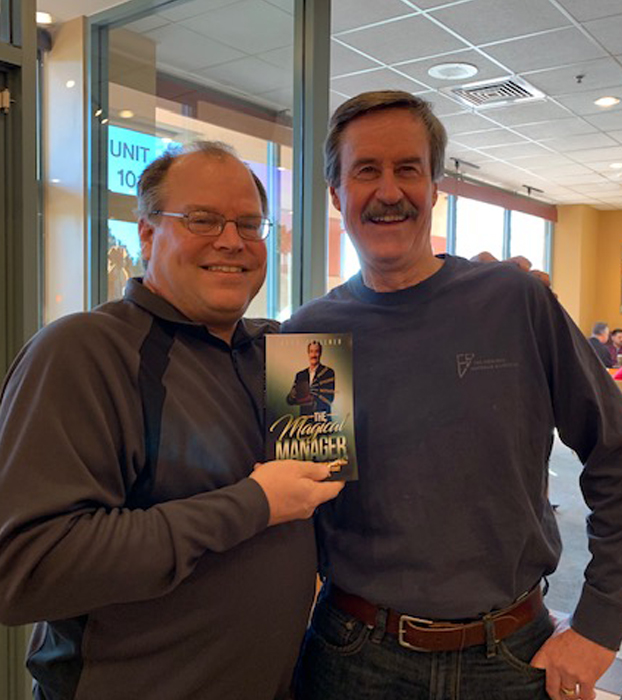 Jack Zoellner giving copy of printed book The Magical Manager to Marty Dickinson